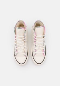 Hochstamm-Sneaker aus cremefarbener Leinwand mit pinkem und grünem gemustertem Besatz, weißen Schnürsenkeln, schwarzer Gummisohle und Metallösen.
