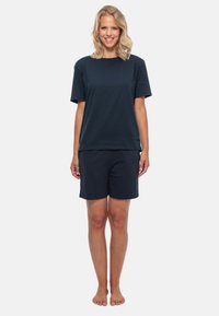 T-shirt in cotone blu navy con maniche corte abbinato a pantaloni corti blu navy. Entrambi i capi hanno una vestibilità ampia e una texture liscia.