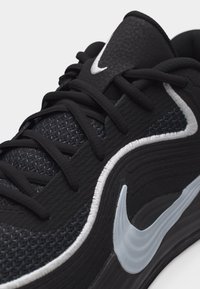 Μαύρο αθλητικό παπούτσι με υφασμένο ανάγλυφο υλικό, μαύρα κορδόνια και λευκό λογότυπο Nike στο πλάι και στη γλώσσα.