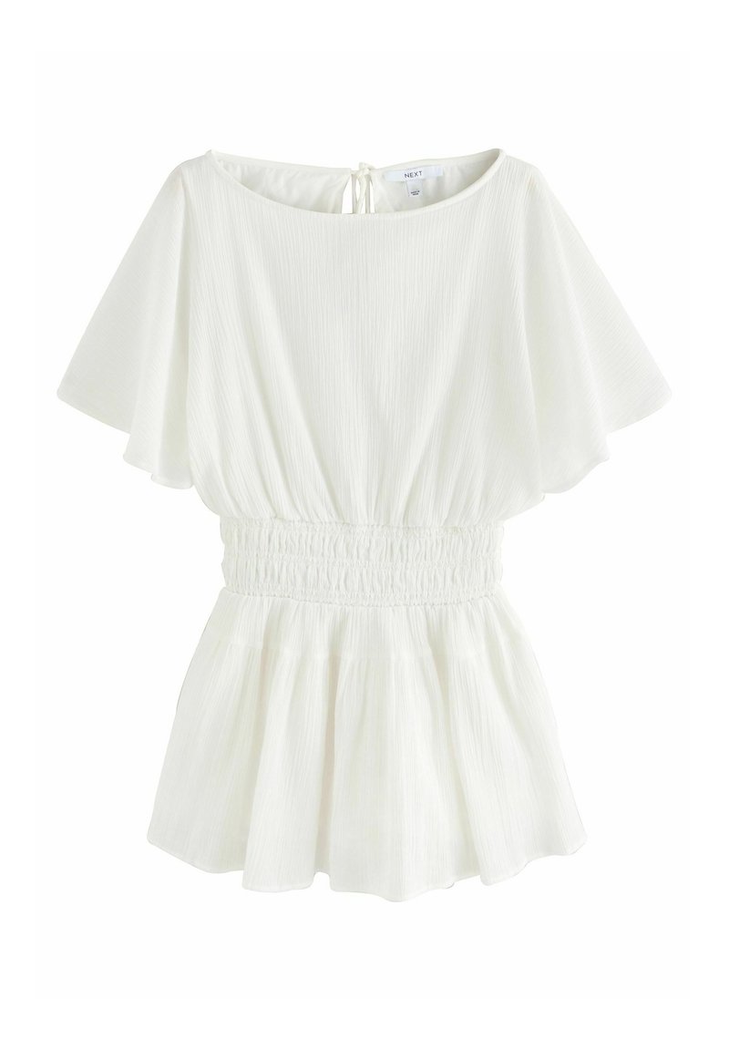 Blouse blanche à manches courtes en tissu texturé, taille élastiquée, ourlet évasé et fermeture à nouer dans le dos au niveau de l'encolure.