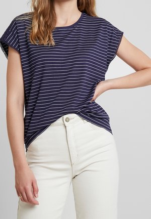 Camiseta de rayas marinas con mangas cortas, con detalles de encaje en las mangas, combinada con unos vaqueros de color claro; textura de tela suave.