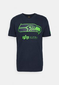 Námorně modré bavlněné tričko s zeleným logem Seattle Seahawks na přední straně, pod grafikou je text "ALPHA INDUSTRIES".