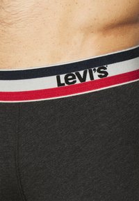 Fekete pamut boxer alsónadrág, fehér, piros és sötétkék csíkos derékrésszel, amelyen a Levi's logó jól láthatóan szerepel.