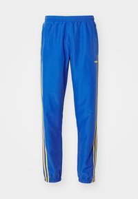 Pantalones deportivos azules hechos de una tela suave, con rayas amarillas a los lados, una cintura elástica y tobillos fruncidos.