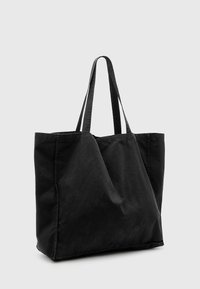 Zwarte katoenen tote bag met dubbele schouderbanden, rechthoekige vorm en zachte textuur. Naaddetails voegen structurele interesse toe.