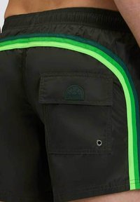 Pantaloni da mare neri con taglio a metà coscia, con accenti verdi e neon, una tasca posteriore e un'etichetta circolare. Texture liscia.