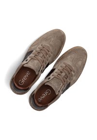 Wildledersneaker in Hellbraun mit dunkelbraunen Akzenten. Merkmale sind eine abgerundete Zehenpartie, Schnürdesign und ein Logo auf den Innensohlen. Gummilaufsohle.