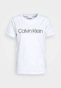 White cotton T-shirt featuring a round neckline and short sleeves, with "Calvin Klein" printed in black, modern font across the front.