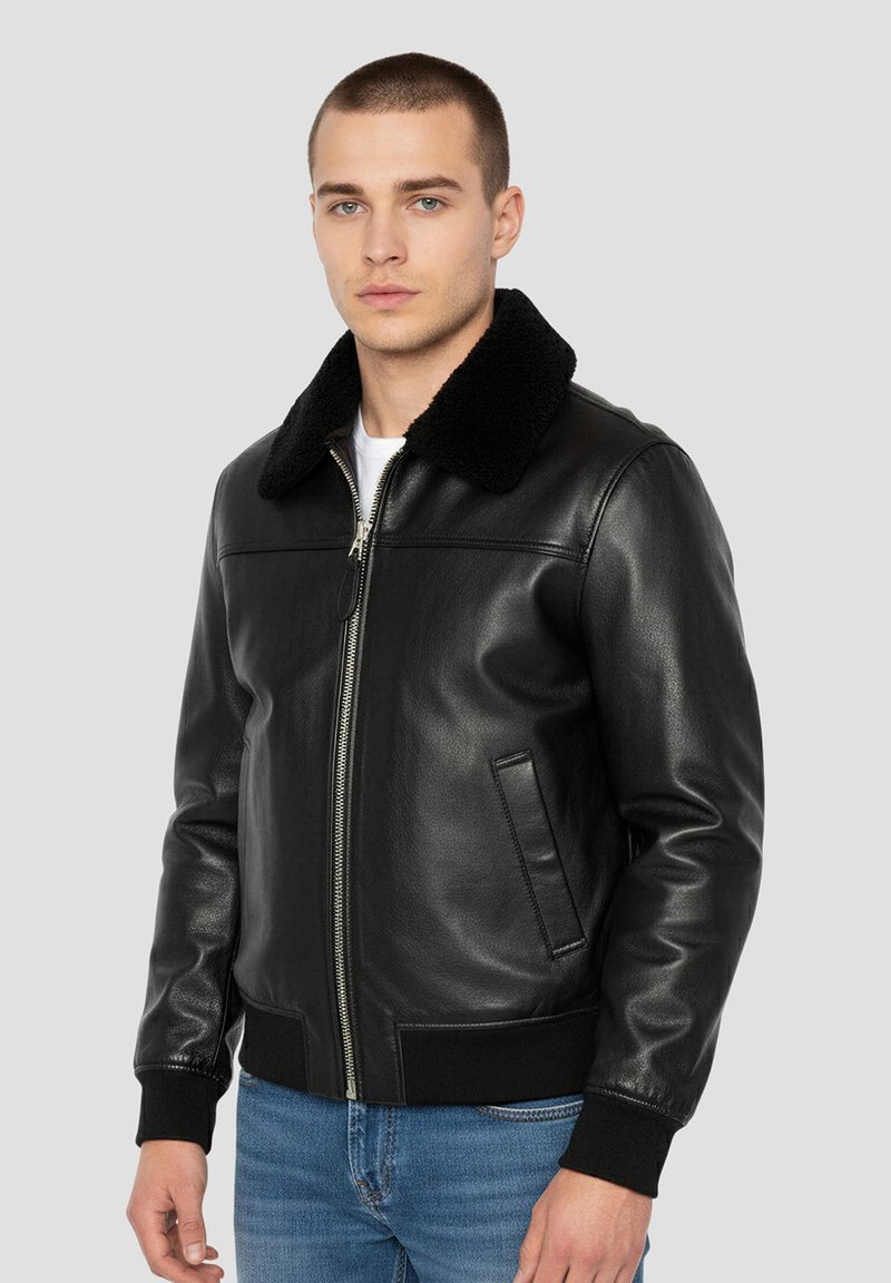 Giacca bomber in pelle nera con morbido colletto in pelliccia nera, cerniera frontale e polsini a coste. Presenta tasche laterali e una texture liscia.