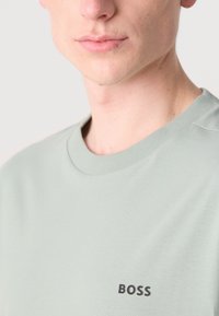 Lys grønn crew neck t-skjorte laget av myk bomull, med en liten svart "BOSS" logo på brystet og ribbet halslinning.