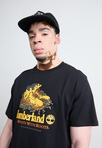 Timberland FRONT BOOT GRAPHIC TEE - Apdrukāts T-krekls - black