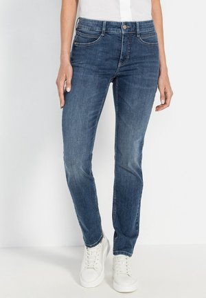 Dunkelblaue Denim-Jeans mit schmaler Passform, fünf Taschen-Design und dezentem Verblassen. Mit weißen Sneakers zur Kontrastierung kombiniert.
