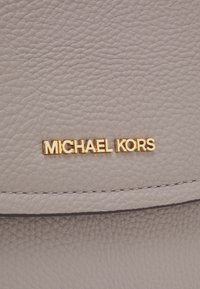 Grey pebbled leather material with a textured finish. Features a gold "MICHAEL KORS" logo prominently displayed. Stitched detail on edges.