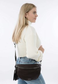 Borsa a tracolla in pelle marrone con forma arrotondata, chiusura con zip e superficie testurizzata. Presenta una lunga tracolla regolabile e un dettaglio a nappina.