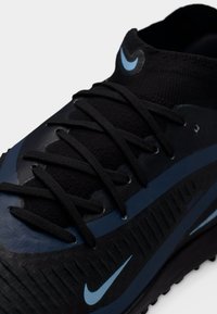 Μαύρο αθλητικό παπούτσι με υφή στην επιφάνεια, μπλε λεπτομέρειες και μαύρα κορδόνια. Διαθέτει εμφανές λογότυπο swoosh και κομψό, ρευστό σχεδιασμό.