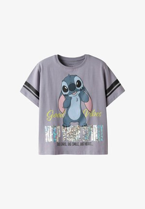 T-shirt gris à manches courtes avec un personnage de dessin animé aux grandes oreilles, un texte coloré et un élément graphique brillant.