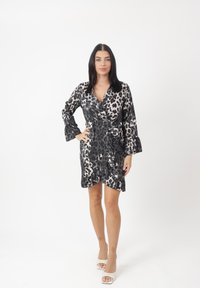 Kleid mit Leopardenmuster in Schwarz- und Beigetönen, mit Wickeldesign, langen Glockenärmel und rüschengesäumtem Saum. Glatte, satinartige Textur.