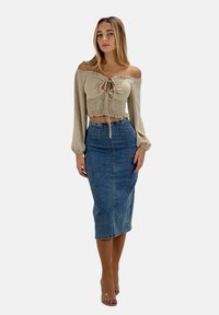 Haut beige à épaule dénudée avec un corsage froncé, associé à une jupe crayon en denim. Texture lisse, design ajusté et coupe longueur genou.