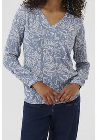 Haut à manches longues et col en V, bleu clair avec motif floral blanc. Tissu texturé avec rayures subtiles. Coupe décontractée avec une silhouette ample.