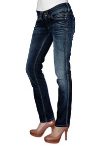 Mörkblå denimjeans med slim fit-design, lätt blekning och kontrastsömmar. Matchas med bruna högklackade skor.