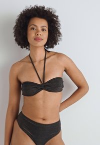 Črni kovinski dvodelni bikini s prepletenim bandeau vrhom in krojem z visokim pasom. Gladka tekstura, tanke naramnice in minimalen dizajn.