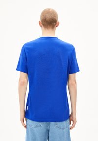 Blaue Baumwoll-T-Shirt mit Rundhalsausschnitt, kurzen Ärmeln und geradem Saum. Verfügt über ein kleines Etikett auf der linken Seite in der Nähe des Saums.