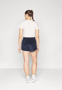 Marineblaue Shorts mit weißen Paspeln, elastischem Bund und weicher Textur. Kombiniert mit einem hellrosa T-Shirt, das einen lässigen Schnitt zeigt.