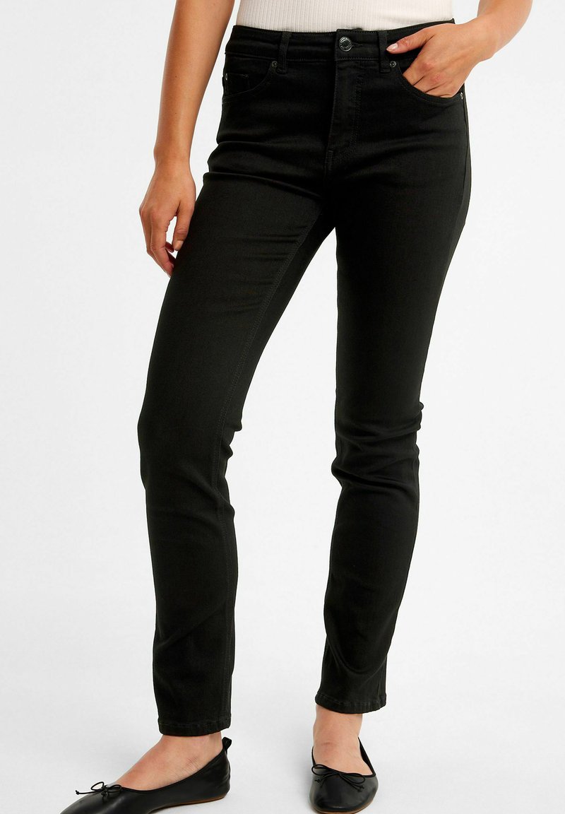 Svarta denim skinny jeans med fem fickor, en knappstängning och subtila sömnadsdetaljer. Bärs med svarta platta skor.