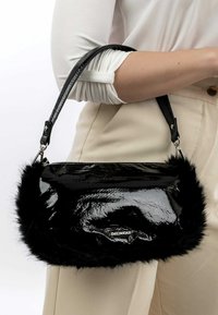 Black patent handbag with faux fur trim, featuring a sleek design, adjustable strap, and silver hardware. Suitable for casual use.