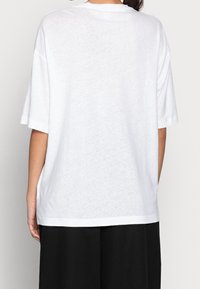 Vit oversized t-shirt med korta ärmar, med rund halsringning och en avslappnad passform. Tyget har en något texturerad yta.
