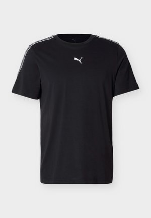 Czarny t-shirt Puma z krótkim rękawem, z białym logo na piersi i charakterystycznymi paskami na ramionach, na jednolitym jasnoszarym tle.