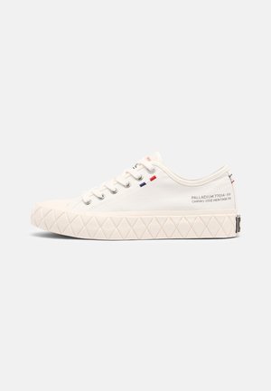 Lage witte canvas sneaker met veters, zool met diamantpatroon en klein rood-wit-blauw vlagdetail vlak bij de hiel.