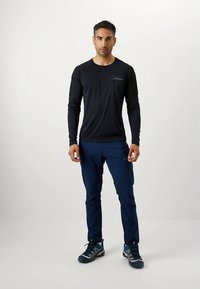 Must musta pika varrukaga särk rinnataskuga, mis on kombineeritud siniste pükste ja hallide spordijalatsitega. Omaduseks on mugav lõige ja hingav kangas.