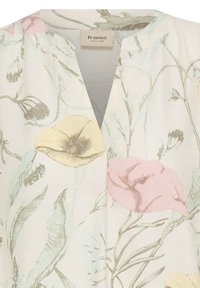Blouse blanche à col en V avec un imprimé floral pastel doux en jaune, rose et vert, avec un col rond et une étiquette mentionnant "fransa since 1968".