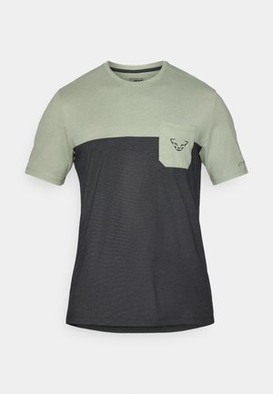 T-skjorte med korte ermer som har en lys grønn øverste del og en mørkegrå nedre del, med en brystlomme og logo-detalj.