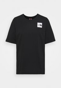 Camiseta negra de manga corta con cuello redondo y un pequeño parche de logo cuadrado blanco de "The North Face" en la parte superior izquierda del pecho.