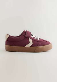 Basket bordeaux pour enfant avec des accents beiges, des lacets blancs, une bride velcro et une semelle en caoutchouc marron sur un fond clair uni.