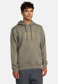 Olivengroene katoenen hoodie met een kangoeroezak, trekkoorden en een vervaagd geel grafisch logo op de borst. Zachte textuur, standaard pasvorm.