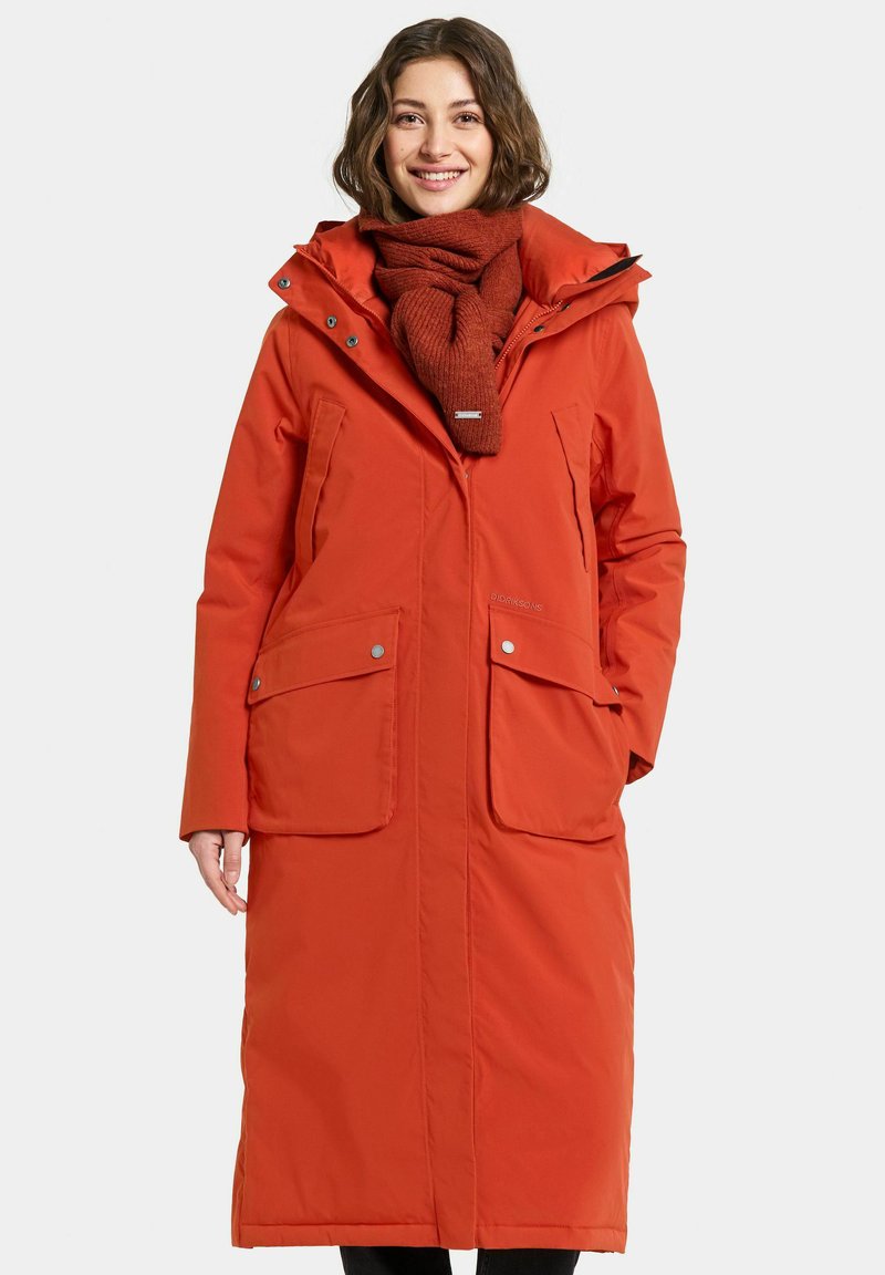 Long orange padded coat with a zippered front, two large pockets, and a fur-lined hood. Pair with a matching knitted scarf.