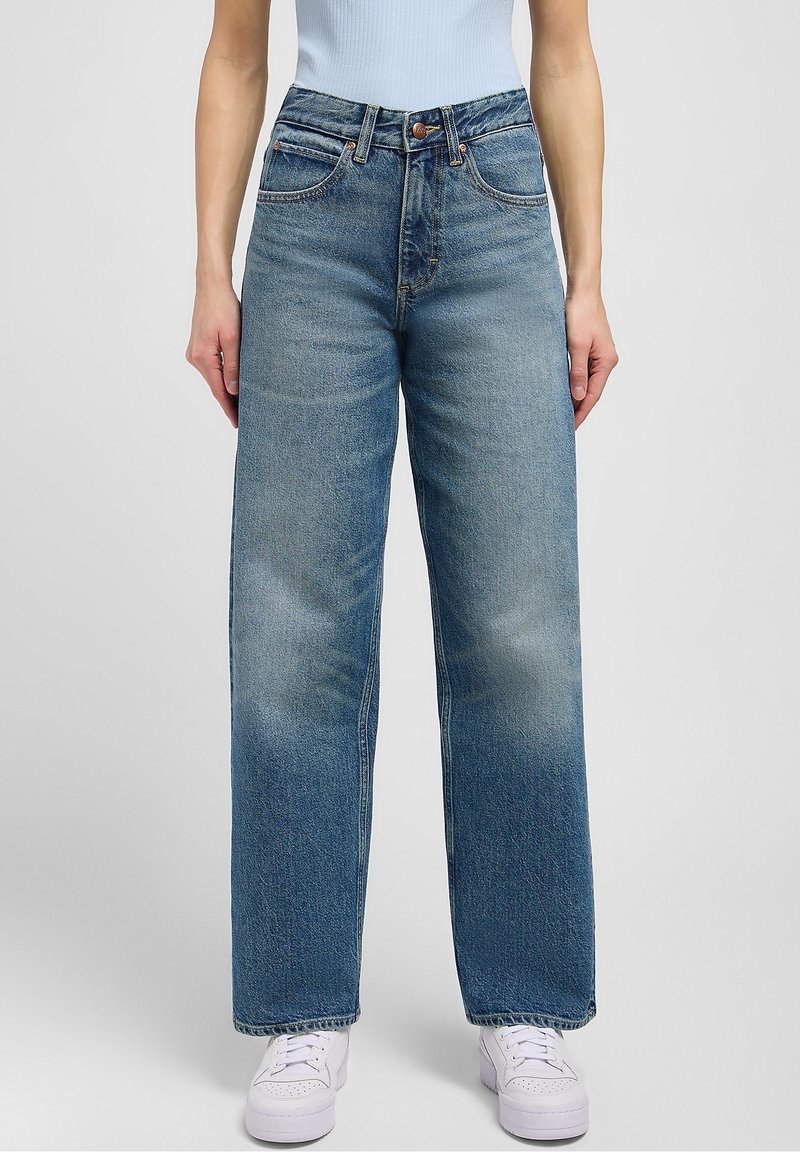 Light blue wide-leg jeans in denim fabric, featuring a high waist, five pockets, and subtle fading on the legs, paired with white sneakers.