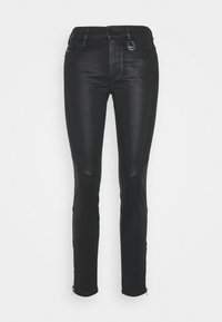 Vaqueros skinny negros de mezclilla. Las características incluyen paneles texturizados en los laterales, puños con cremallera y un botón metálico en la parte frontal con un lazo.