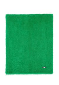 Tapis textile vert et duveteux avec une texture douce. Forme carrée avec un bord lisse et une petite étiquette métallique à un coin.