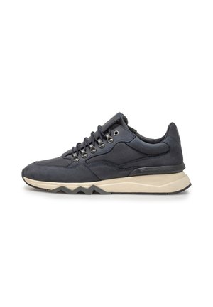 Donkerblauwe sneaker met zwarte veters, metalen oogjes en een dikke beige zool met zwart zigzagloopvlak, van opzij weergegeven op een witte achtergrond.
