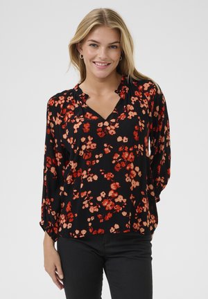 Sort bluse med rød og ferskenfarvet blomstermotiv, lange ærmer, V-udskæring og samling langs udskæringen. Struktureret stof.