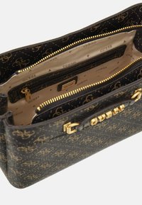 Černá kabelka s vzorem, která má zlaté kování, více oddílů a hladký povrch s logem na vnější straně.