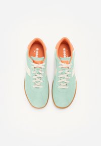 Light teal suede sneakers with a cream stripe, orange interior, and beige laces. Rubber sole with textured pattern for grip.
