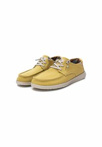 Zapatillas de lona amarillas con perfil bajo, puntera redondeada y suela de goma gris clara. Presenta cordones a juego y forro interior con un patrón.