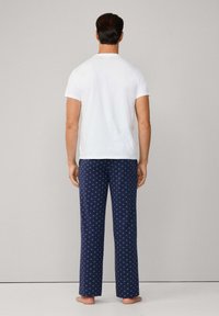 Bílý tričko s krátkým rukávem spárované s námořnickými pyžamovými kalhotami s geometrickým vzorem ve světle modré, vyrobené z měkké tkaniny.