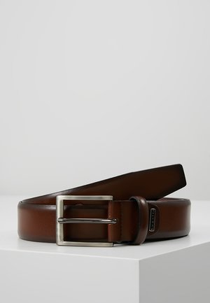 Cinturón de cuero marrón con una textura suave, hebilla rectangular de metal plateado y un sutil acento de marca, descansando sobre una superficie de color claro.