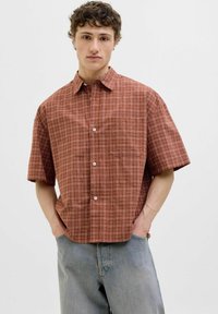 Camisa de cuadros marrón de manga corta, hecha de tela ligera. Presenta un collar abotonado, un bolsillo delantero y un corte relajado.